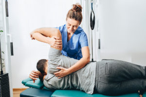 Physiotherapist treatment patient. She holding patient's hand, shoulder joint treatment
