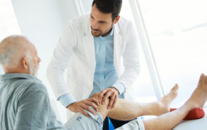 Senior man having his knee examined by a doctor.