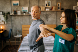 Older man doing exercises with his doctor
