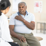A man talking to his orthopedic doctor about a possible shoulder replacement procedure.