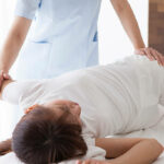 Massage therapist massaging slender woman's legs