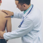 Doctor analysing causes of back pain with stethoscope on hospital