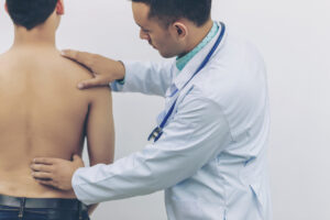 Doctor analysing causes of back pain with stethoscope on hospital