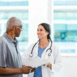 The mid adult female doctor and her senior adult male patient discuss the home healthcare options listed in the brochure.