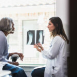 A serious female orthopedic doctor shows a senior female patient an x-ray of the patient's fractured foot.