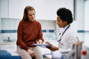 Happy woman going through her medical data with Physical Medicine Expert