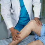 Asian senior or elderly old lady woman patient show her scars surgical total knee joint replacement Suture wound surgery arthroplasty on bed in nursing hospital ward : healthy strong medical concept.