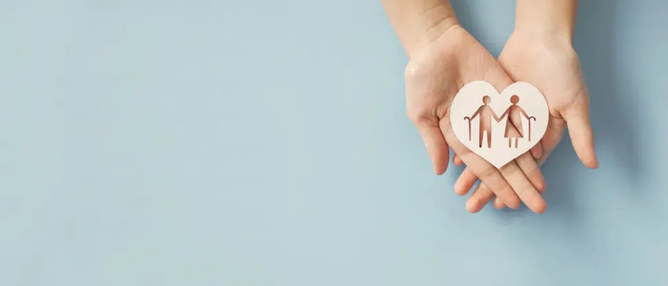 Image of a heart with an elderly couple cut out of the middle, placed on top of a person's hands to signify healthy aging. 