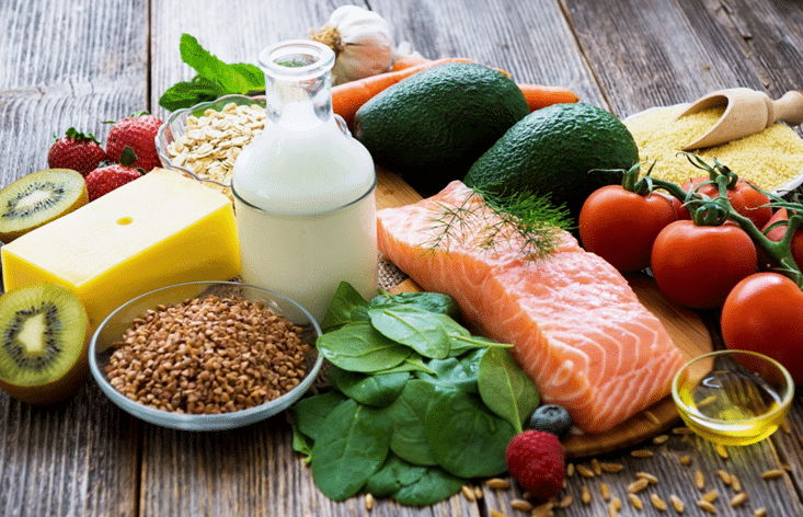 Image of fresh fruits, vegetables, grains, and fish laid out on a table to represent strong bones and healthy aging. 