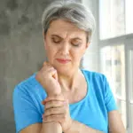Elderly woman holding her wrist due to orthopedic pain.
