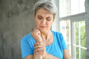 Elderly woman holding her wrist due to orthopedic pain.